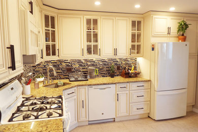 Example of a small classic l-shaped laminate floor and beige floor enclosed kitchen design in New York with an undermount sink, raised-panel cabinets, beige cabinets, granite countertops, brown backsplash, mosaic tile backsplash, white appliances, no island and orange countertops