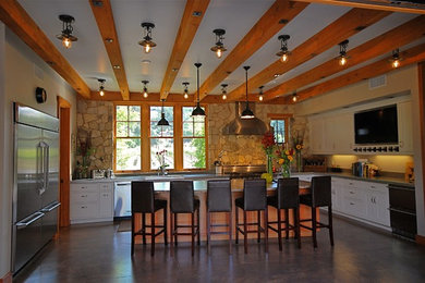 Example of a large classic u-shaped concrete floor eat-in kitchen design in San Francisco with shaker cabinets, white cabinets, solid surface countertops, stainless steel appliances and an island