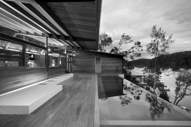 This is an example of a large contemporary courtyard rectangular infinity pool in Sydney with decking and a hot tub.