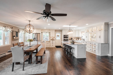 Inspiration for a huge cottage medium tone wood floor and brown floor eat-in kitchen remodel in Baltimore with a farmhouse sink, white cabinets, granite countertops and two islands