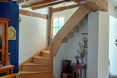 Imagen de escalera curva campestre grande con escalones de madera y contrahuellas de madera