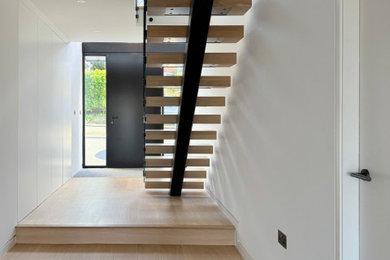 Medium sized contemporary wood floating metal railing staircase in Sussex with metal risers.