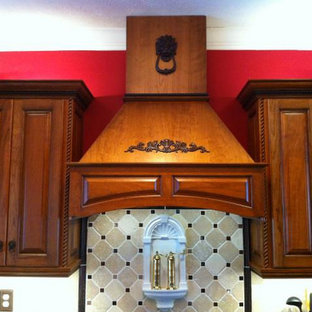 Mid-sized kitchen pantry appliance - Example of a mid-sized l-shaped kitchen pantry design in Huntington with raised-panel cabinets, medium tone wood cabinets, soapstone countertops and stone tile backsplash