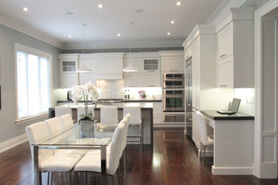 Example of a transitional l-shaped dark wood floor kitchen design in Toronto with an undermount sink, shaker cabinets, white cabinets, quartz countertops, gray backsplash, stone tile backsplash, stainless steel appliances and an island