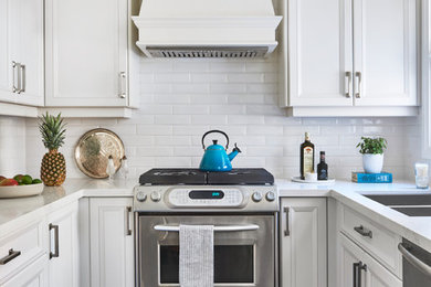 This is an example of a traditional u-shaped separate kitchen in Toronto with a double-bowl sink, recessed-panel cabinets, white cabinets, white splashback, subway tile splashback and stainless steel appliances.