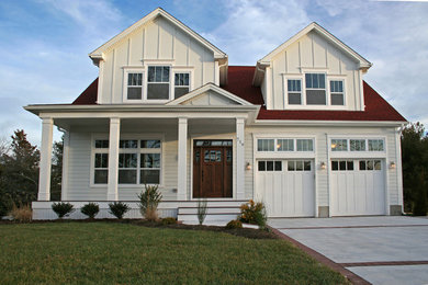 Imagen de fachada de casa beige y roja tradicional de dos plantas con revestimiento de vinilo, tejado a dos aguas, tejado de teja de madera y tablilla