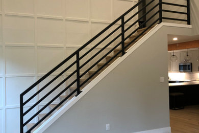 Example of a large urban metal straight metal railing and wood wall staircase design in Vancouver with wooden risers