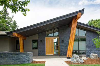 Example of a large mid-century modern gray one-story mixed siding house exterior design in Denver with a shed roof