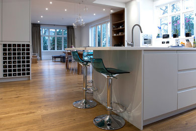 This is an example of a contemporary open plan kitchen in Hertfordshire with dark hardwood floors.