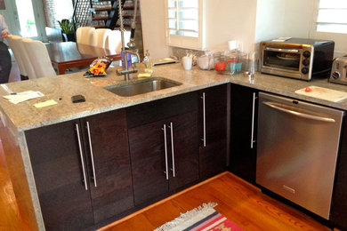 Inspiration for a medium tone wood floor kitchen remodel in DC Metro with a single-bowl sink, flat-panel cabinets, dark wood cabinets and stainless steel appliances