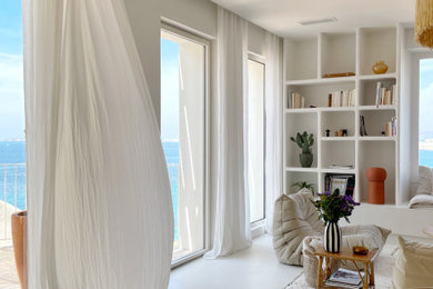 Imagen de biblioteca en casa abierta y blanca y madera mediterránea con paredes blancas, suelo de cemento y suelo blanco