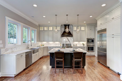 Large arts and crafts u-shaped medium tone wood floor and brown floor eat-in kitchen photo in DC Metro with a farmhouse sink, raised-panel cabinets, beige cabinets, granite countertops, beige backsplash, stone slab backsplash, stainless steel appliances and an island