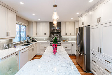 Inspiration for a large transitional u-shaped medium tone wood floor eat-in kitchen remodel in Calgary with an undermount sink, shaker cabinets, white cabinets, gray backsplash, glass tile backsplash, stainless steel appliances, an island and marble countertops