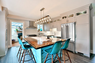 Mid-sized eclectic enclosed kitchen photo in Toronto with a farmhouse sink, shaker cabinets, gray backsplash, stainless steel appliances and an island