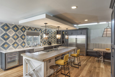 Design ideas for a large midcentury single-wall eat-in kitchen in DC Metro with a farmhouse sink, flat-panel cabinets, grey cabinets, quartz benchtops, grey splashback, cement tile splashback, stainless steel appliances, light hardwood floors and with island.