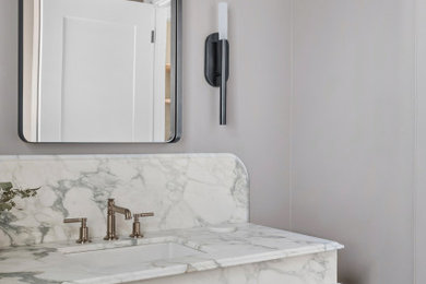 Inspiration for a transitional ceramic tile and gray floor powder room remodel in Other with shaker cabinets, light wood cabinets, marble countertops, multicolored countertops and a built-in vanity