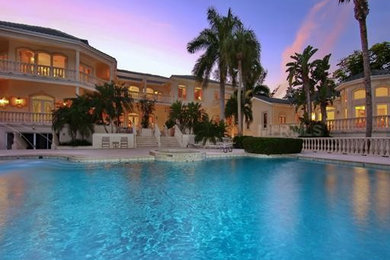Ejemplo de casa de la piscina y piscina alargada exótica grande a medida en patio trasero con entablado
