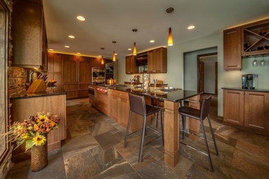 Expansive transitional l-shaped eat-in kitchen in Milwaukee with an undermount sink, shaker cabinets, medium wood cabinets, granite benchtops, stone tile splashback, stainless steel appliances, porcelain floors and with island.