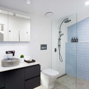 Photo of a small industrial master bathroom in Brisbane with flat-panel cabinets, grey cabinets, an open shower, a one-piece toilet, blue tile, ceramic tile, white walls, ceramic floors, a vessel sink, solid surface benchtops, brown floor, an open shower, white benchtops and a floating vanity.