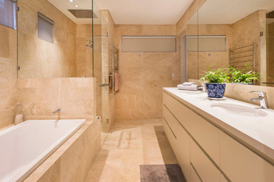 Modern master bathroom in Other with a drop-in tub, beige tile, travertine, beige walls, travertine floors, beige floor, a hinged shower door, a double vanity and a built-in vanity.