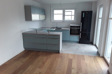 Offene Moderne Küche in U-Form mit blauen Schränken und Halbinsel in Dortmund