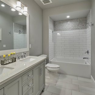 Idée de décoration pour une salle de bain craftsman de taille moyenne pour enfant avec un placard à porte shaker, des portes de placard blanches, un combiné douche/baignoire, un WC à poser, un carrelage multicolore, un carrelage en pâte de verre, un mur gris, un sol en carrelage de porcelaine, un lavabo encastré et un sol gris.
