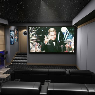 Cette image montre une grande salle de cinéma minimaliste fermée avec un mur multicolore, moquette, un écran de projection et un sol multicolore.