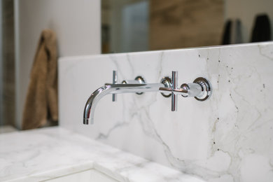 Cette photo montre une salle de bain moderne en bois clair avec un plan de toilette en marbre et meuble-lavabo suspendu.
