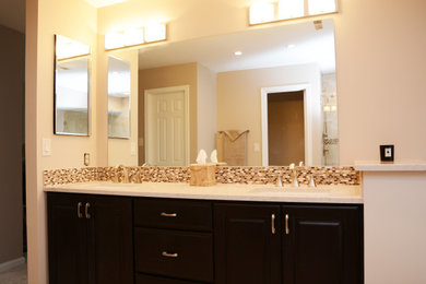 Mid-sized elegant master beige tile beige floor and double-sink bathroom photo in DC Metro with raised-panel cabinets, dark wood cabinets, beige walls, an undermount sink, quartz countertops, a hinged shower door, beige countertops and a built-in vanity