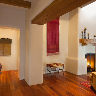 Offenes, Großes, Repräsentatives, Fernseherloses Mediterranes Wohnzimmer mit beiger Wandfarbe, braunem Holzboden, Kamin und verputztem Kaminsims in Albuquerque
