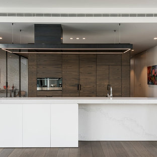 Contemporary kitchen pantry ideas - Kitchen pantry - contemporary galley kitchen pantry idea in Christchurch with marble countertops, black appliances, an island and medium tone wood cabinets