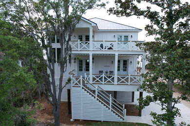 Imagen de fachada de casa blanca y negra costera de tres plantas con revestimiento de vinilo, tejado a dos aguas, tejado de metal y panel y listón