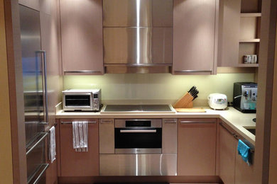 Example of a mid-sized u-shaped beige floor and light wood floor kitchen design in New York with an undermount sink, flat-panel cabinets, light wood cabinets, quartz countertops, beige backsplash, glass sheet backsplash, stainless steel appliances, no island and beige countertops