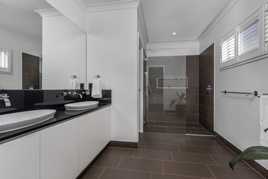 This is an example of a mid-sized contemporary bathroom in Brisbane with flat-panel cabinets, white cabinets, porcelain tile, white walls, porcelain floors, engineered quartz benchtops, an open shower and black benchtops.
