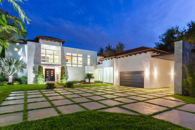 Large mediterranean white two-story stucco house exterior idea in Miami with a hip roof and a tile roof
