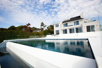 Huge trendy backyard tile and rectangular infinity pool fountain photo in New York