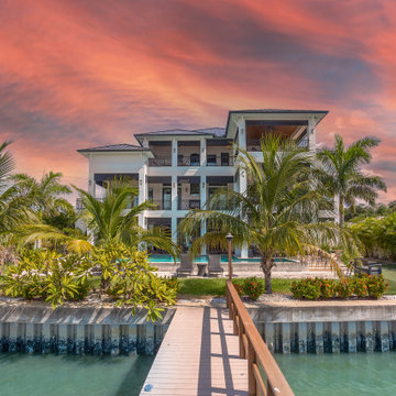 Tropical Waterfront Villa With Tiered Balconies, Palm-Lined Grounds, and Sunset-