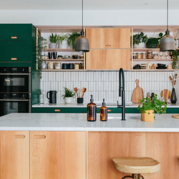 Open plan green plywood kitchen