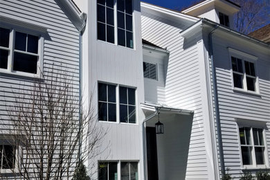 Large elegant white three-story wood exterior home photo in New York with a shingle roof