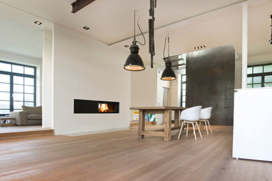 Großes, Repräsentatives, Fernseherloses Modernes Wohnzimmer im Loft-Stil mit weißer Wandfarbe, braunem Holzboden, Kaminofen, verputzter Kaminumrandung und beigem Boden in München