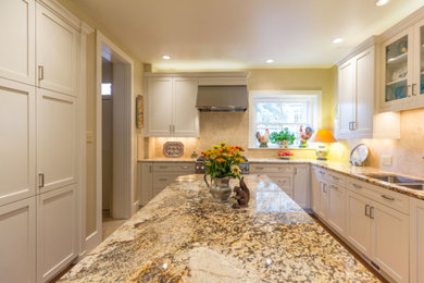 Example of a large transitional u-shaped brown floor and medium tone wood floor enclosed kitchen design in Denver with a double-bowl sink, shaker cabinets, white cabinets, granite countertops, beige backsplash, ceramic backsplash, stainless steel appliances and an island