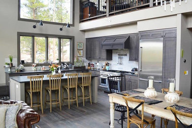 Open concept kitchen - large rustic l-shaped dark wood floor and gray floor open concept kitchen idea in Denver with an undermount sink, shaker cabinets, gray cabinets, gray backsplash, stone tile backsplash, stainless steel appliances and an island