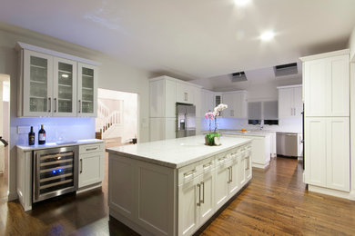 Trendy eat-in kitchen photo in New York with an undermount sink, shaker cabinets, white cabinets, marble countertops, white backsplash and stainless steel appliances