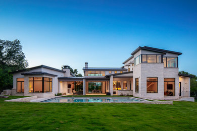 Inspiration for a huge contemporary gray two-story stone exterior home remodel in Austin with a metal roof