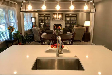 Example of a large transitional open concept carpeted and gray floor family room design in Detroit with gray walls, a standard fireplace, a brick fireplace and a wall-mounted tv