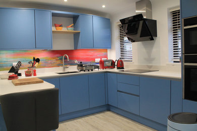 Inspiration for a medium sized contemporary u-shaped enclosed kitchen in Other with a submerged sink, flat-panel cabinets, blue cabinets, quartz worktops, multi-coloured splashback, glass sheet splashback, stainless steel appliances, laminate floors, a breakfast bar, brown floors and white worktops.