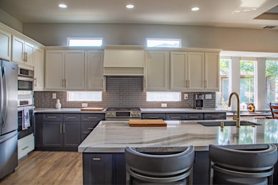 Example of a mid-sized transitional l-shaped porcelain tile eat-in kitchen design in Sacramento with raised-panel cabinets, glass tile backsplash and beige countertops