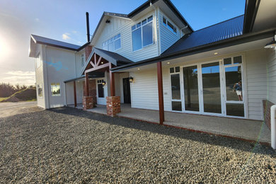 Inspiration for a country two-storey white house exterior in Melbourne with concrete fiberboard siding, a gable roof, a metal roof and a black roof.