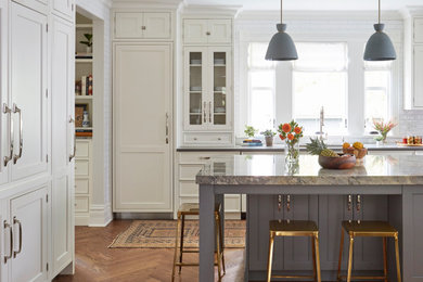 Inspiration for a transitional l-shaped kitchen in Chicago with an undermount sink, recessed-panel cabinets, white cabinets, panelled appliances, medium hardwood floors, with island, brown floor and grey benchtop.