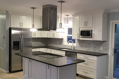 Mid-sized trendy l-shaped light wood floor open concept kitchen photo in New York with an undermount sink, shaker cabinets, white cabinets, quartzite countertops, multicolored backsplash, stone tile backsplash, stainless steel appliances and an island